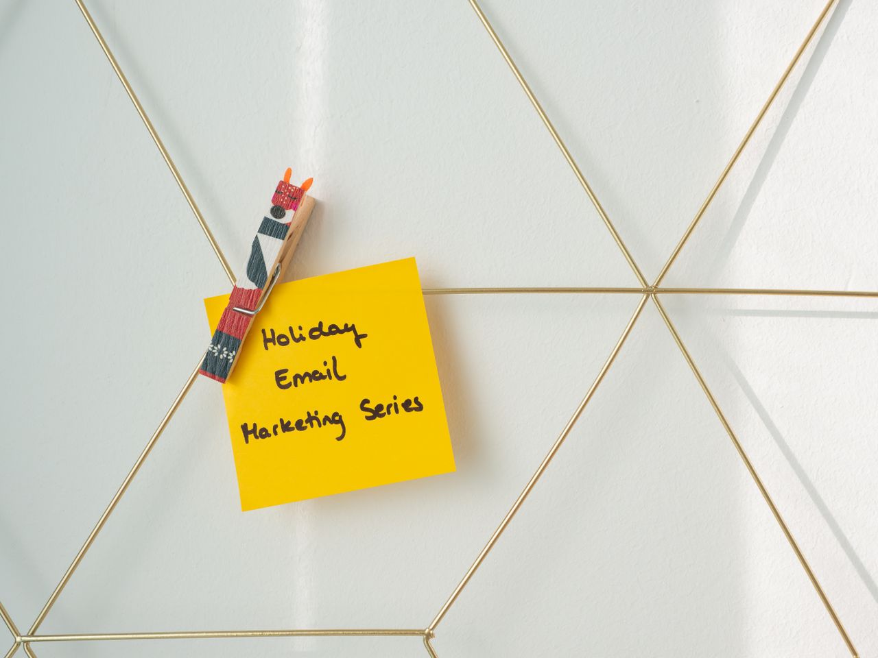 about-01 Bright yellow sticky note with holiday email marketing message clipped to a wireframe wall.